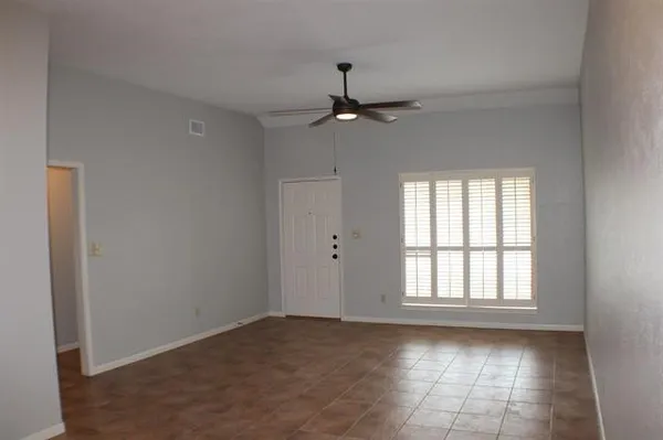 an empty room with chandelier fan and windows