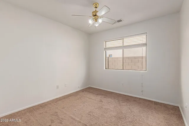 an empty room with windows and ceiling fan