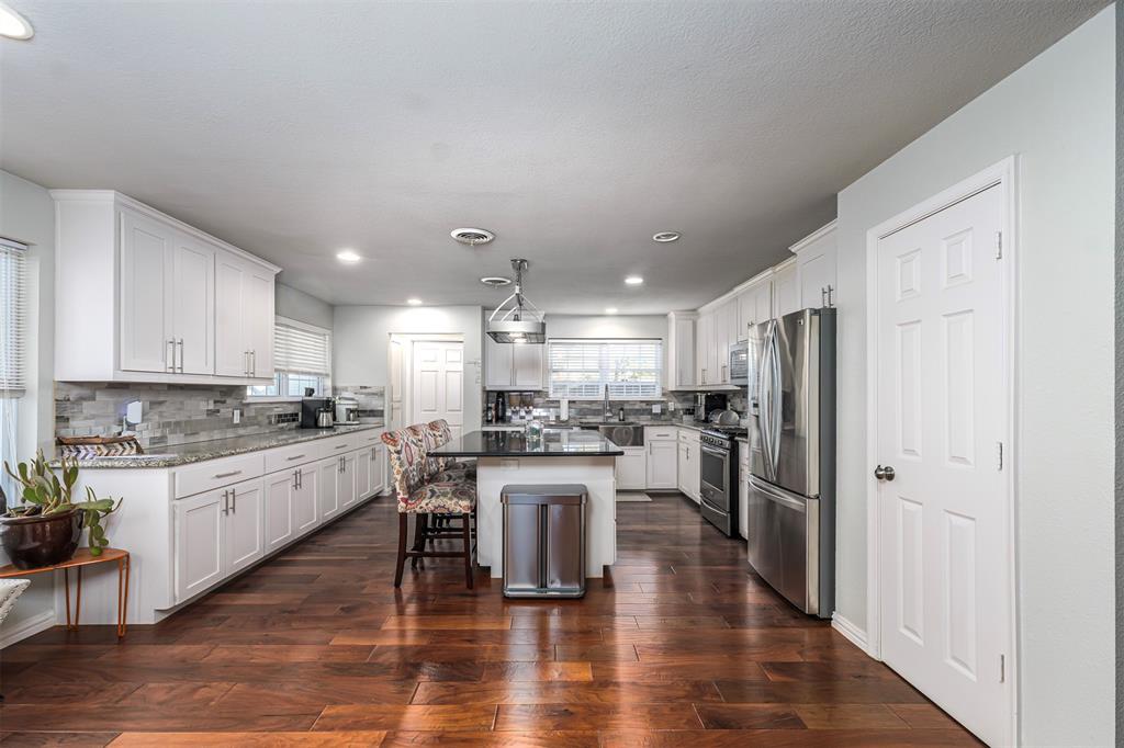 6512 Greenway Road Fort Worth, TX 76116 - Photo 9 of 38 Kitchen with appliances with stainless steel finishes, white cabinetry, a kitchen breakfast bar, dark wood-type flooring, and a kitchen island