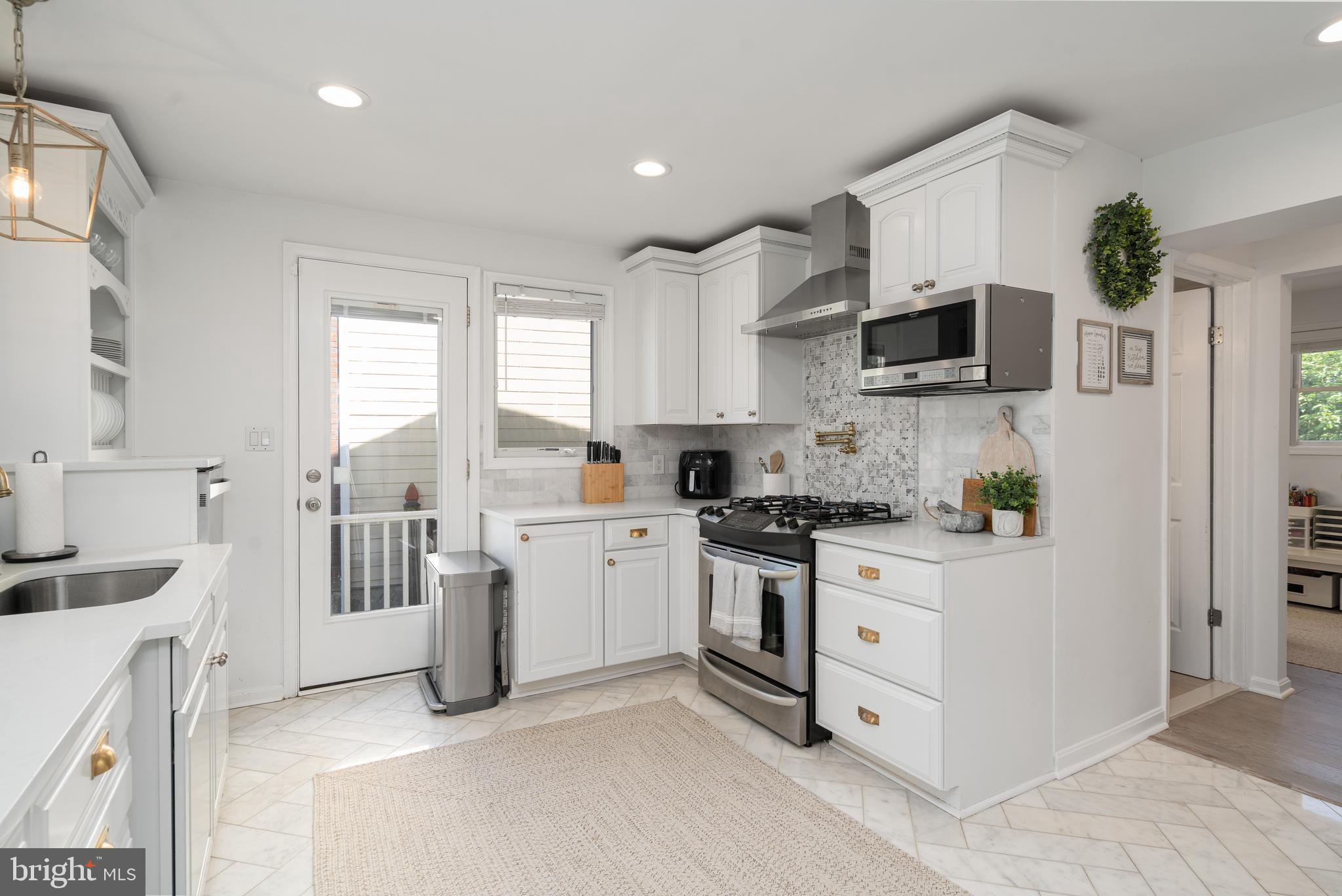 6401 Winnepeg Road Bethesda, MD 20817 - Photo 12 of 41 a kitchen with stainless steel appliances white cabinets a sink a stove a refrigerator and a microwave
