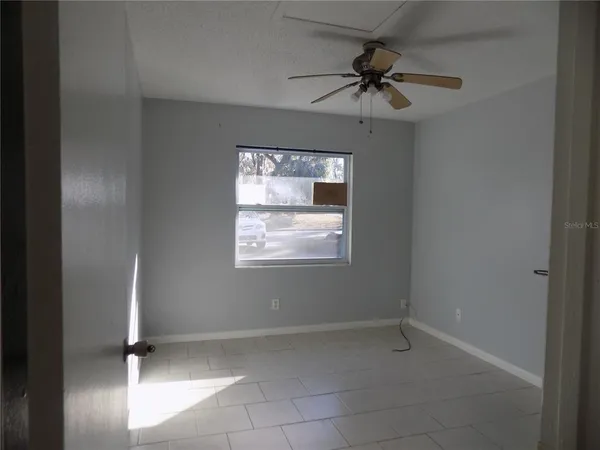 an empty room with a window and a fan