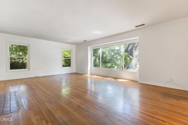 a view of an empty room with wooden floor and windows