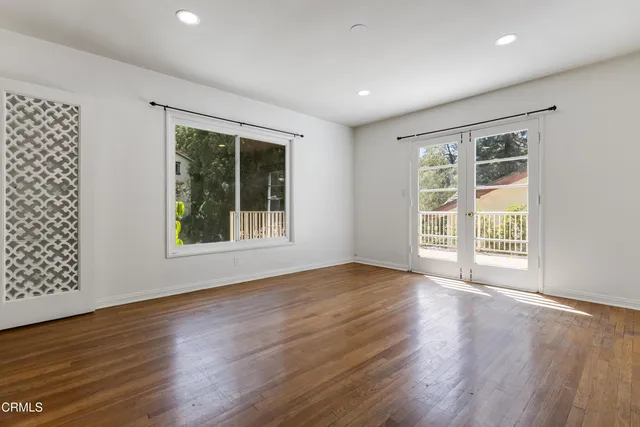 a view of an empty room with wooden floor and a window