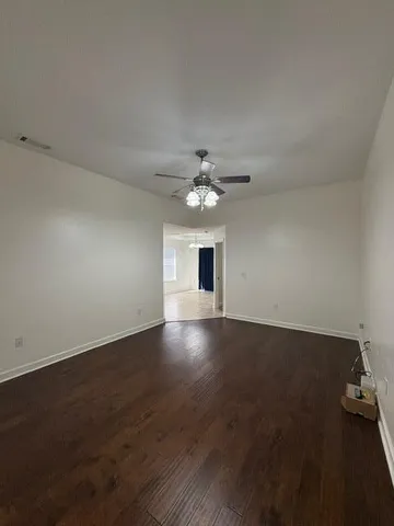 an empty room with wooden floor chandelier fan and windows