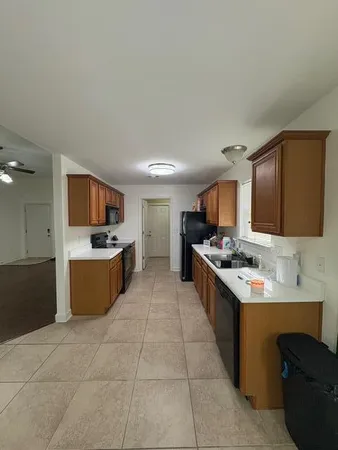 a large kitchen with a stove a sink a counter top space and cabinets