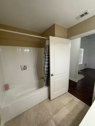 an empty room with a chandelier fan and windows