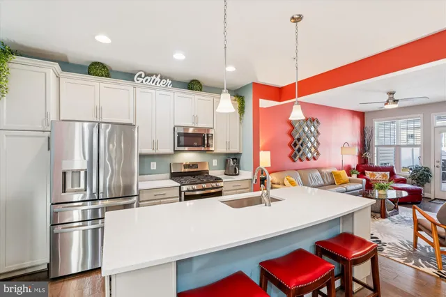 a kitchen with stainless steel appliances a refrigerator a stove a sink dishwasher a dining table and chairs with wooden floor