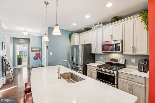 a kitchen with stainless steel appliances a stove a sink a microwave a refrigerator and cabinets