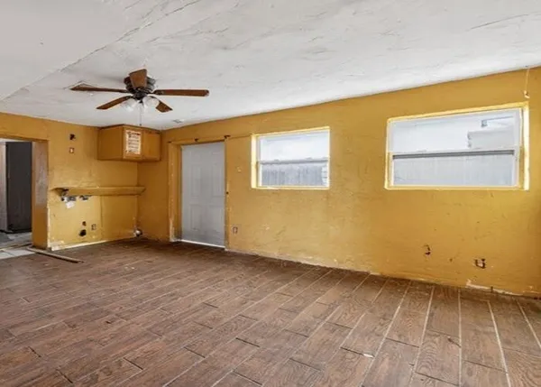 a view of an empty room with a window and wooden floor