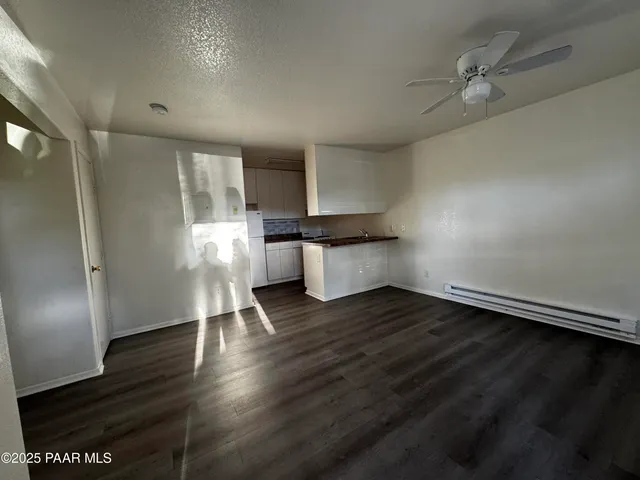an empty room with wooden floor cabinet and windows