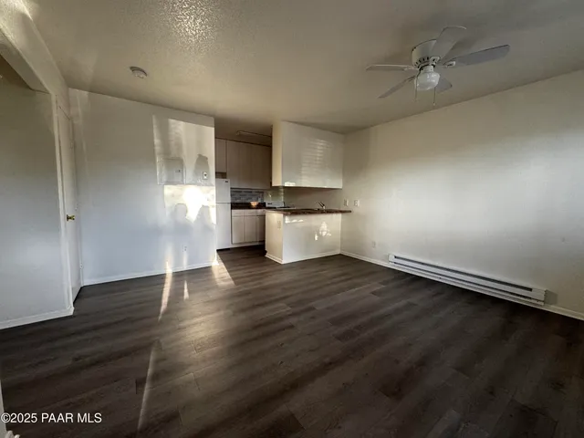 an empty room with wooden floor and stainless steel appliances