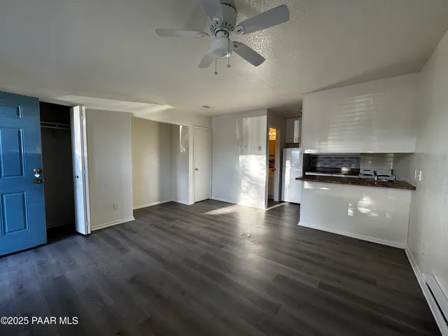 a view of an empty room with kitchen and a window
