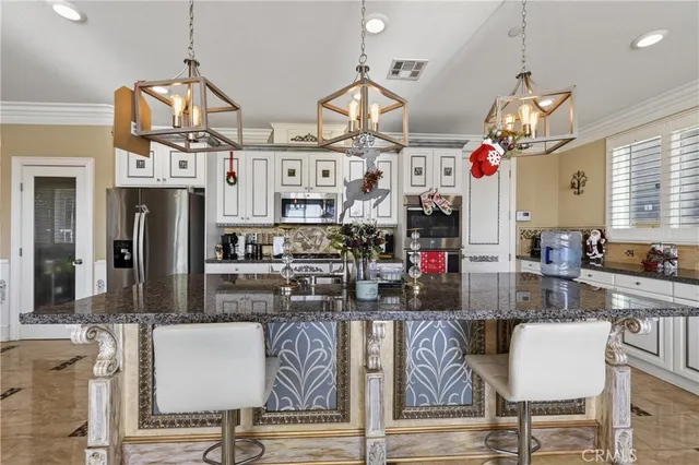 a living room with stainless steel appliances kitchen island granite countertop furniture and a chandelier