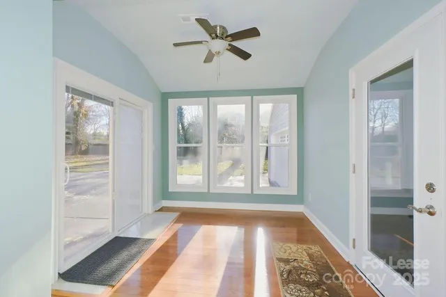 a view of empty room with wooden floor and fan