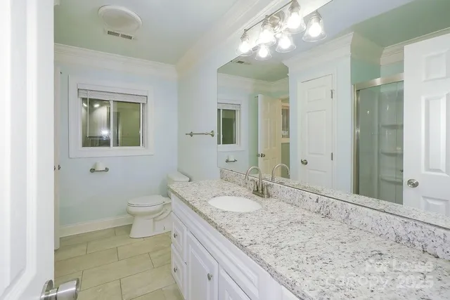 a bathroom with a granite countertop sink a toilet and a mirror
