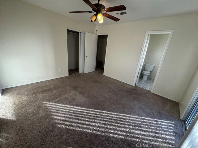 an empty room with a fan & a window