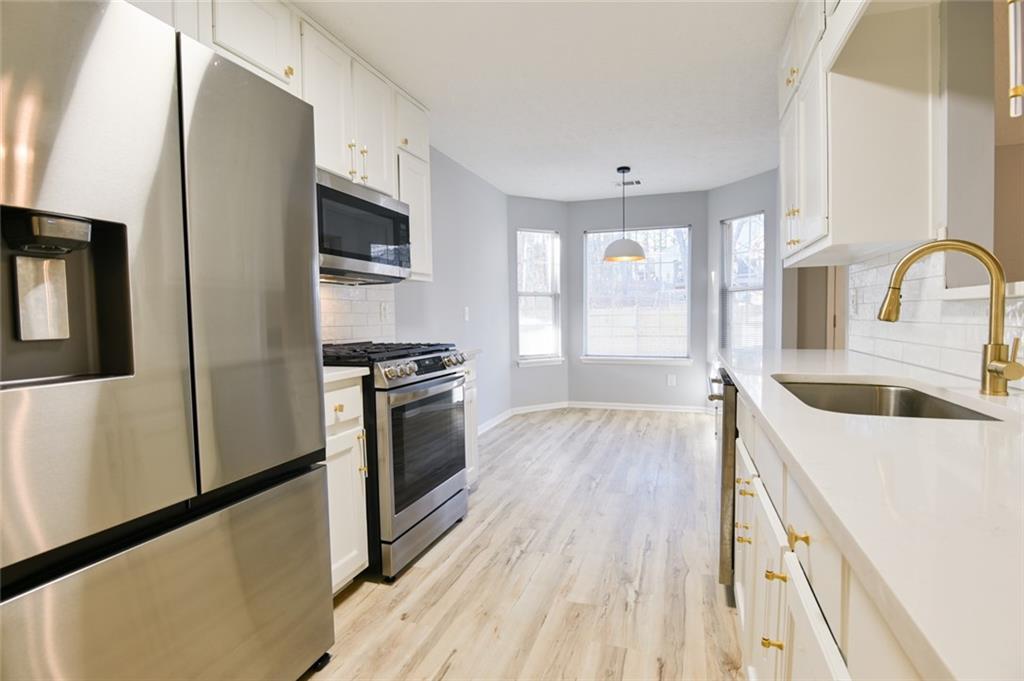 1255 Summit Point Lane Snellville, GA 30078 - Photo 11 of 41 a kitchen with stainless steel appliances granite countertop a refrigerator a stove and a sink with wooden floor