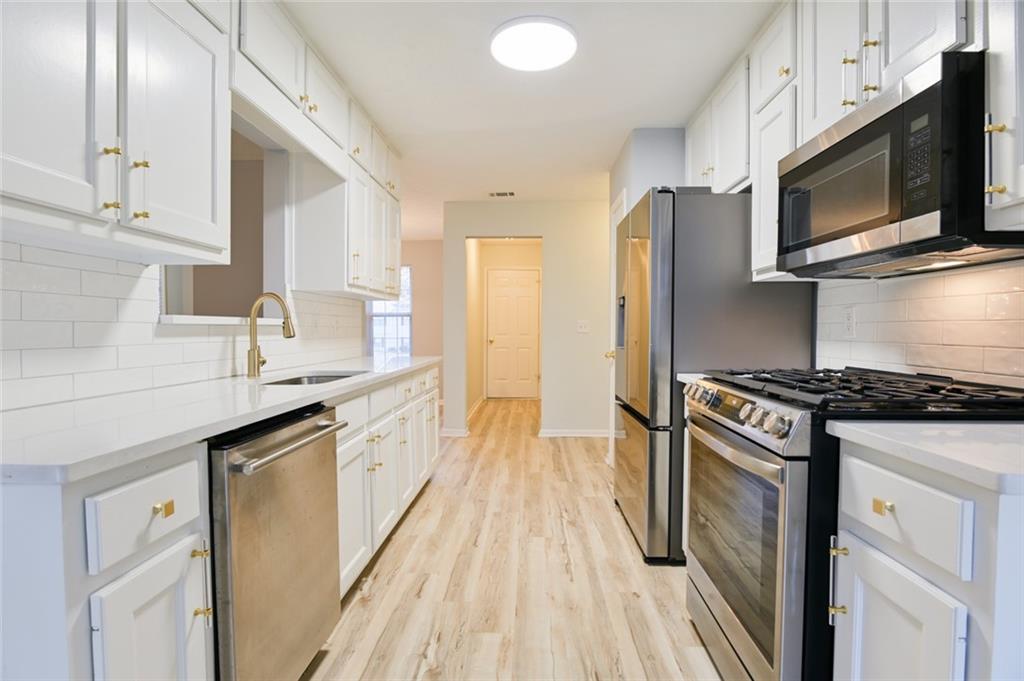 1255 Summit Point Lane Snellville, GA 30078 - Photo 12 of 41 a kitchen with stainless steel appliances a sink dishwasher stove and microwave with wooden floor
