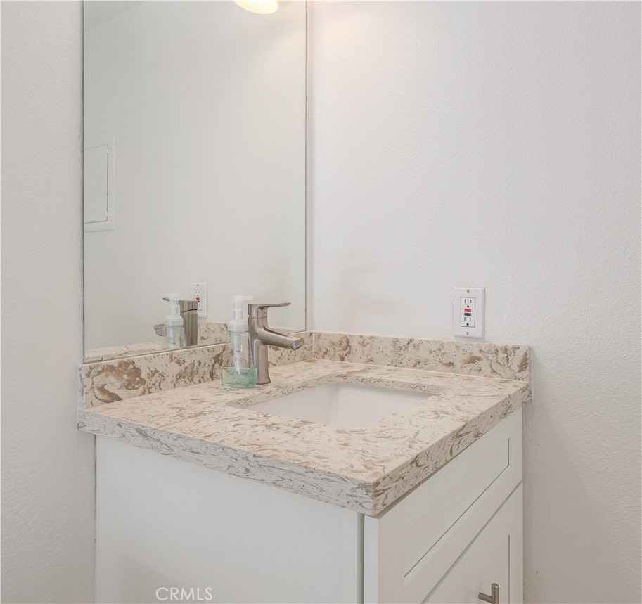 12660 Briarglen Loop, Unit G Stanton, CA 90680 - Photo 15 of 38 a bathroom with a granite countertop sink and white cabinets