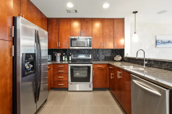 a kitchen with stainless steel appliances granite countertop a stove top oven a sink dishwasher a refrigerator and white cabinets with wooden floor