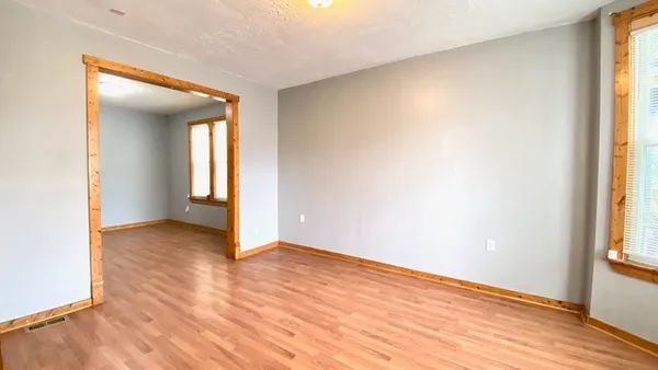 an empty room with wooden floor and windows
