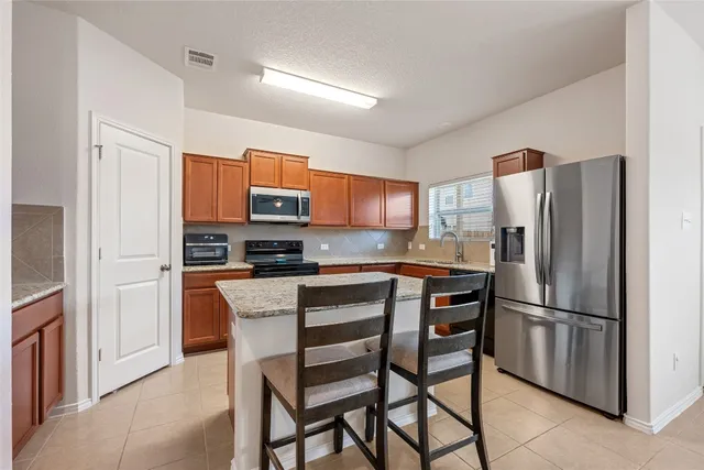 a kitchen with stainless steel appliances granite countertop a refrigerator and a stove top oven