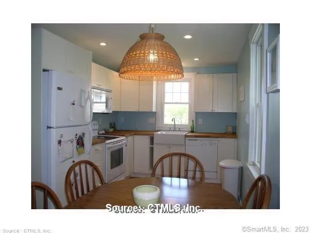 a kitchen with a stove a sink dishwasher a dining table and chair with wooden floor