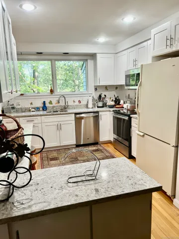 a kitchen with granite countertop a sink stainless steel appliances and window