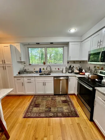 a large kitchen with granite countertop a stove a sink dishwasher and a microwave oven with cabinets