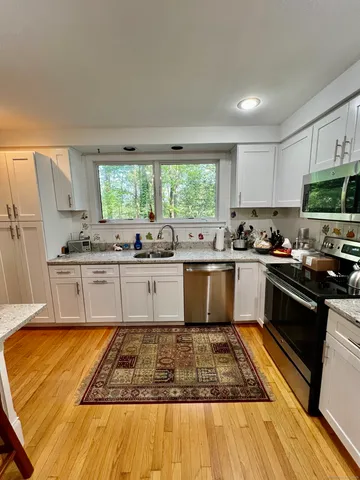 a large kitchen with granite countertop a stove a sink dishwasher and a microwave oven with cabinets