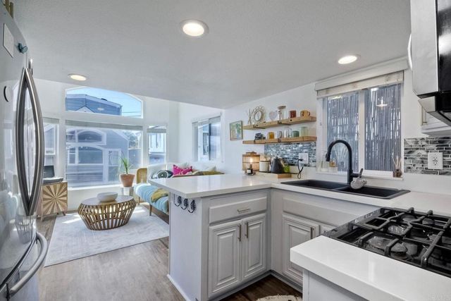 a kitchen with stainless steel appliances a stove a refrigerator a sink dishwasher with a dining table and chairs