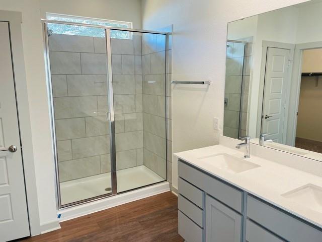 161 Filifera Court Leander, TX 78641 - Photo 6 of 13 Bathroom with a shower stall, wood finished floors, double vanity, and a spacious closet