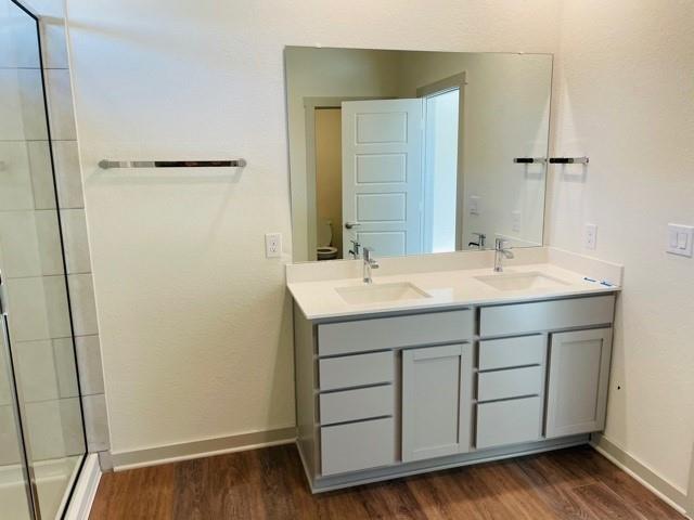 161 Filifera Court Leander, TX 78641 - Photo 8 of 13 Bathroom with wood finished floors, double vanity, baseboards, and tiled shower