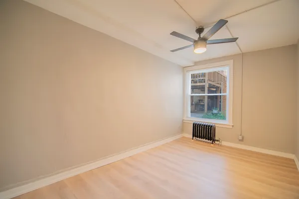 an empty room with a window and ceiling fan