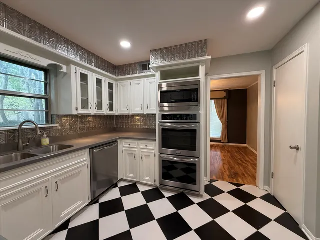 a kitchen with granite countertop a stove and white cabinets
