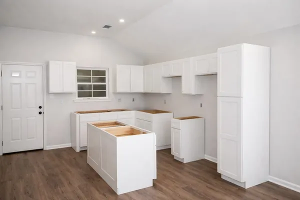 a kitchen with a sink a stove cabinets and wooden floor
