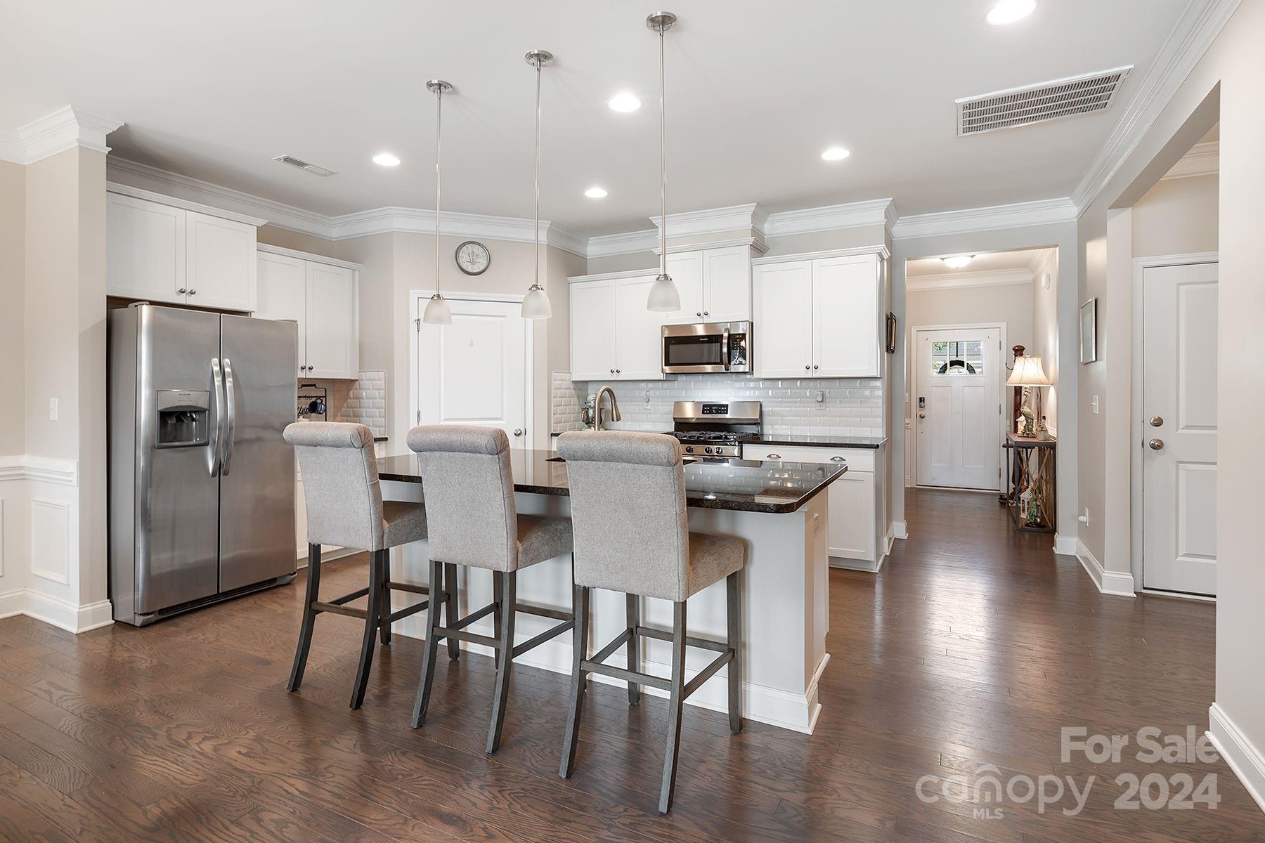 118 East Northstone Road Mooresville, NC 28115 - Photo 4 of 33 a kitchen with stainless steel appliances kitchen island granite countertop a dining table chairs refrigerator and sink