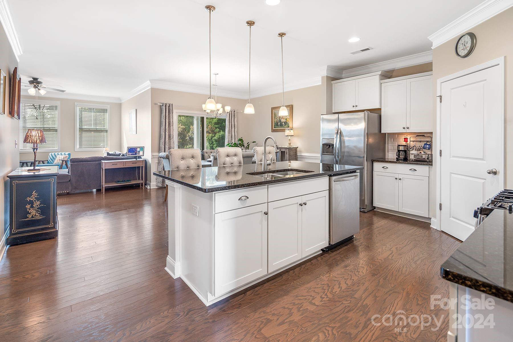 118 East Northstone Road Mooresville, NC 28115 - Photo 7 of 33 a kitchen with stainless steel appliances kitchen island granite countertop a stove a sink a refrigerator and white cabinets with wooden floor