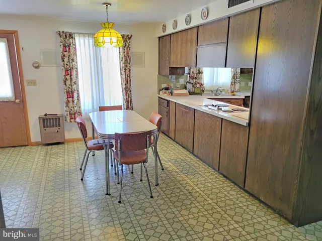 a dining room with stainless steel appliances kitchen island granite countertop a table chairs and a refrigerator