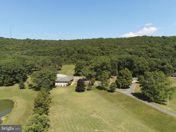 an aerial view of a house with a yard and trees all around