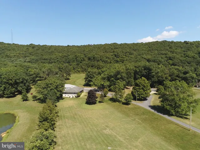 an aerial view of a house with a yard and trees all around