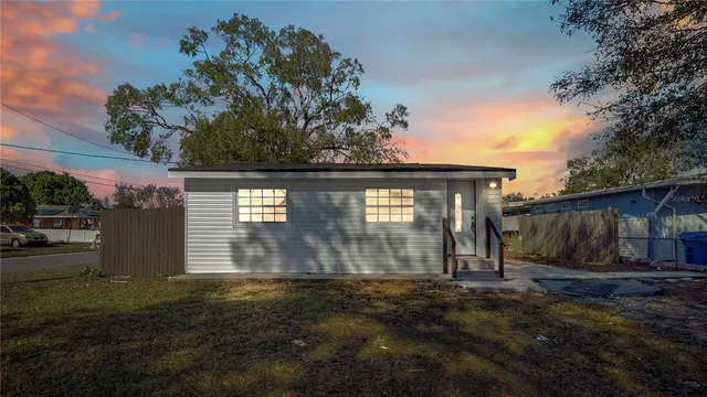 a view of a white house next to a yard with large trees