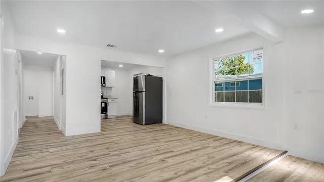 a view of empty room with wooden floor and fan