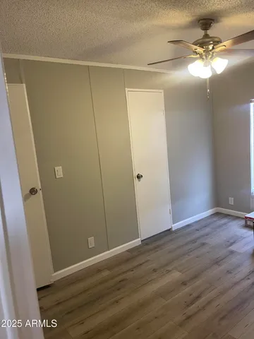 an empty room with wooden floor and fan