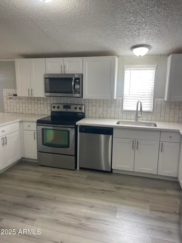 a kitchen with stainless steel appliances granite countertop a stove a sink and a microwave