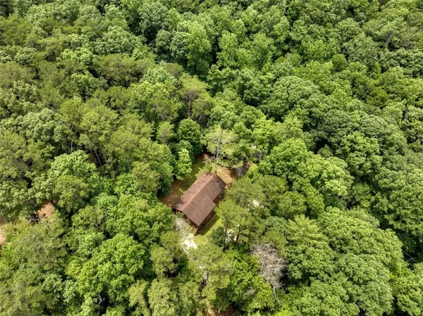 an aerial view of residential house with outdoor space and trees all around