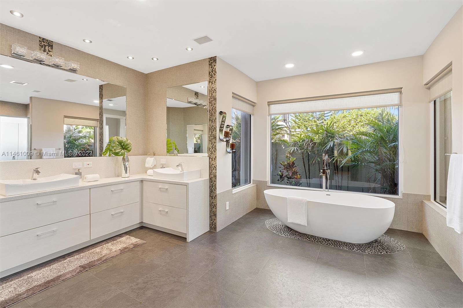 3088 Birkdale Drive Weston, FL 33332 - Photo 26 of 41 a bathroom with a double vanity sink a large mirror and a bathtub