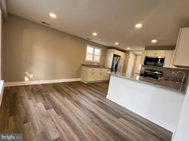 a view of kitchen appliances wooden floor and cabinets