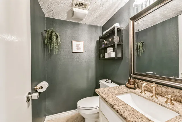 a bathroom with a granite countertop sink a toilet and a mirror