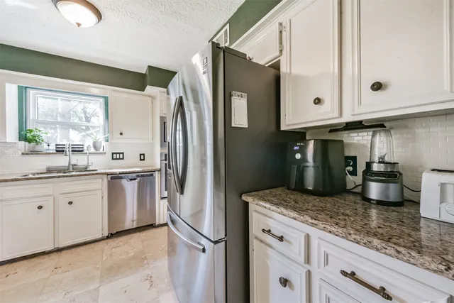 a kitchen with granite countertop a sink stove and refrigerator